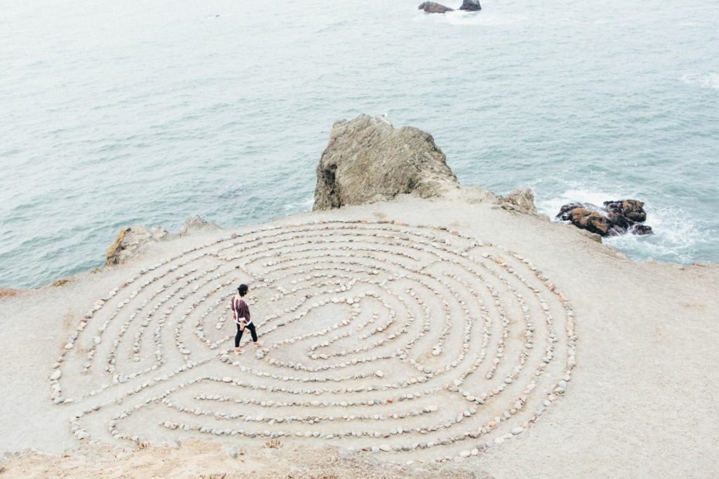 person walking in a maze made out of rocks on a beach