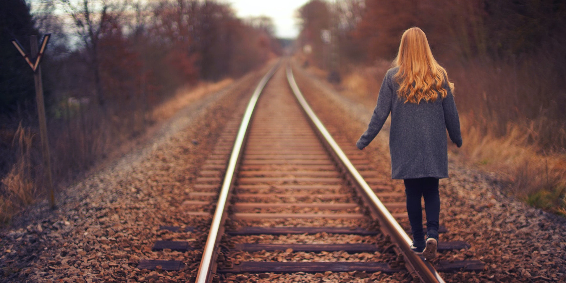 woman walking on a railway track away from camera
