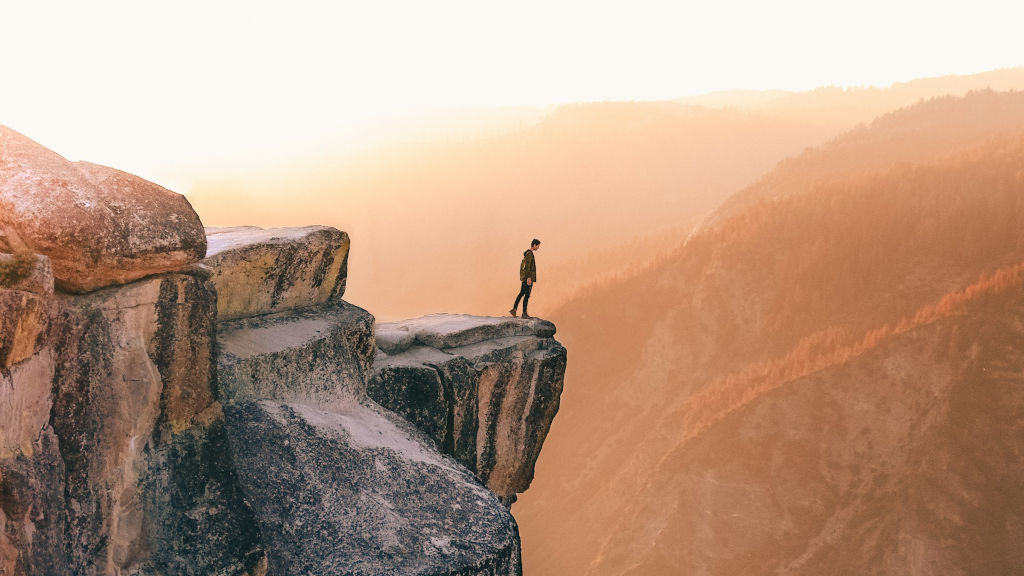 man standing at cliff around sunset